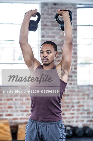 Muscular man lifting kettle bells