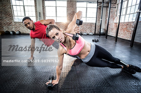 Fit couple doing push ups with dumbbells