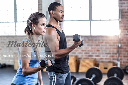 Fit couple doing dumbbell exercises