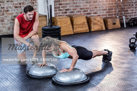 Male trainer assisting woman with push ups