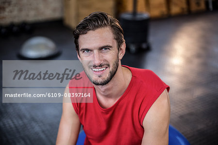 Smiling trainer sitting on medicine ball