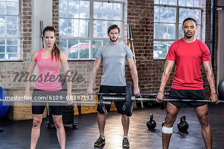 Three fit sporty people lifting barbell