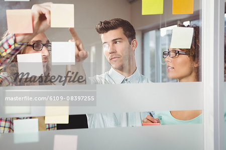 Creative businessmen pointing at sticky notes in office