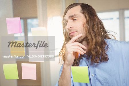 Thoughtful businessman watching at sticky notes