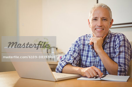 Happy creative businessman with hand on chin in office