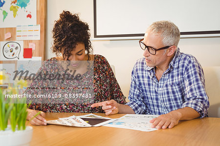 Creative business people discussing over documents in office