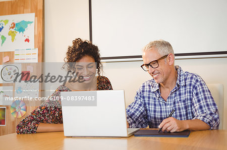 Business people discussing over laptop in office