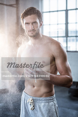 Fit shirtless man chalking his hands