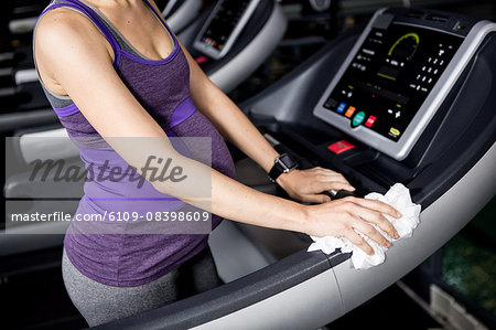 Pregnant woman wiping the treadmill