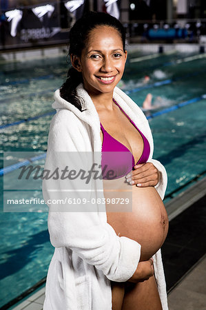 Pregnant woman in swinsuits touching her belly