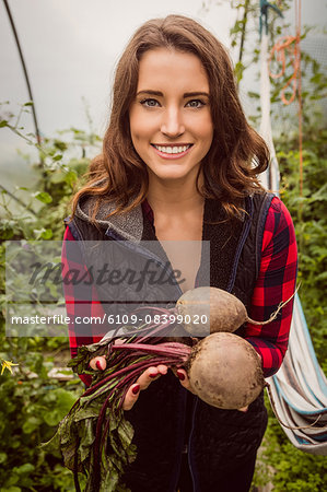 Smiling woman holding and showing beetroot
