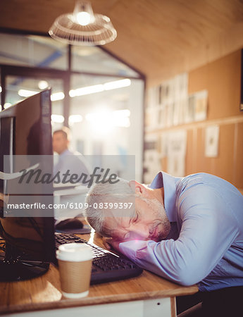 Tired businessman falling asleep on his desk