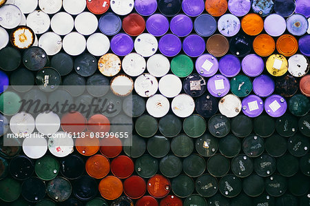 Large pile of colorful petroleum barrels stacked up in colour co-ordinated way.