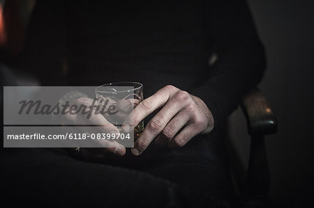 A man's hands holding a glass of whisky.