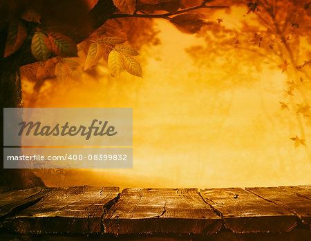 Wooden table. Autumn design with leaves falling in  forest and empty display. Space for your montage. Season fall background