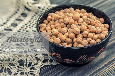 Raw chickpeas in wooden bowl on wooden background with with rustic doily crochet