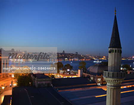 Evening view of  Istanbul and Bosphorus. The city is illuminated. Minaret is in foreground.
