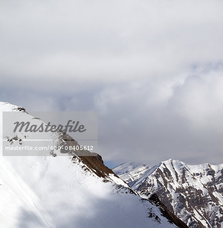 Snowy slope and sky with clouds at sun day. Caucasus Mountains, Georgia. View from ski resort Gudauri.