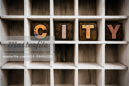 The word "CITY" written in vintage ink stained wooden letterpress type in a partitioned printer's drawer.