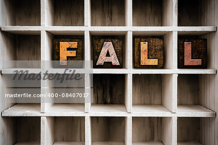 The word "FALL" written in vintage ink stained wooden letterpress type in a partitioned printer's drawer.