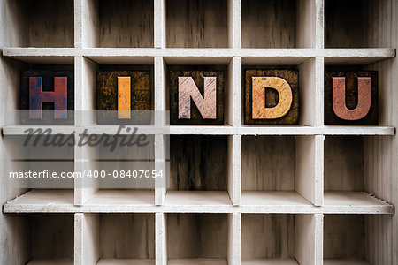 The word "HINDU" written in vintage ink stained wooden letterpress type in a partitioned printer's drawer.