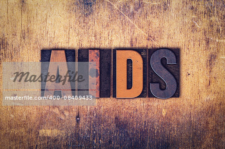 The word "AIDS" written in dirty vintage letterpress type on a aged wooden background.