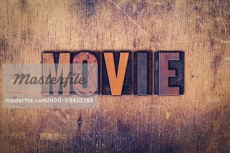 The word "Movie" written in dirty vintage letterpress type on a aged wooden background.