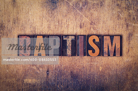 The word "Baptism" written in dirty vintage letterpress type on a aged wooden background.