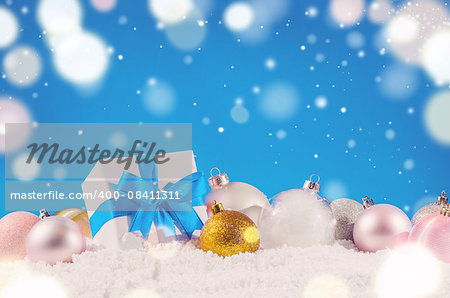 white decorative christmas gift box with ribbon and balls on snow against blue festive background