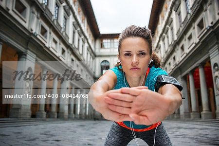 Now it is time to invest in your body and no matter you are at hometown or traveling. Sportswoman with headset is stretching next to Uffizi gallery in Florence Italy