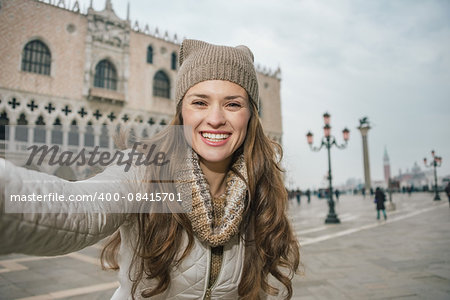 Delightful Venice, Italy can help make the most of your next winter getaway. Smiling young woman tourist taking selfie on St. Mark's Square near Dogi Palace
