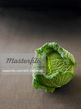 A Savoy cabbage on a grey surface