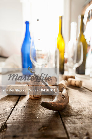 A corkscrew, corks, empty wine bottles and glasses