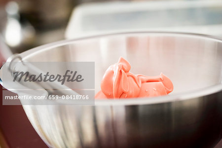 Pink meringue for making macaroons in a mixing bowl