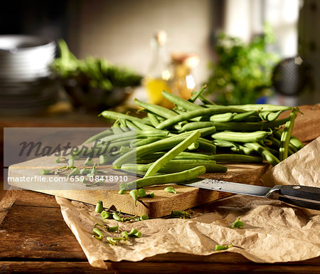 Green beans being chopped on a wooden board in a kitchen