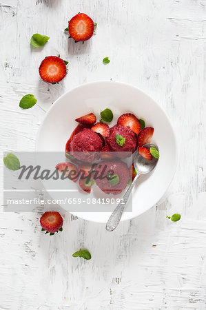 Strawberry sorbet with fresh mint on a white plate (seen from above)