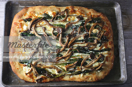 Pan pizza with mushrooms and spinach on a baking tray