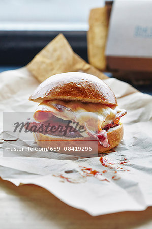 A bacon and cheese burger on a piece of paper