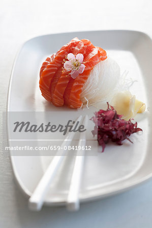 Salmon sashimi on radish strips with a cherry flower