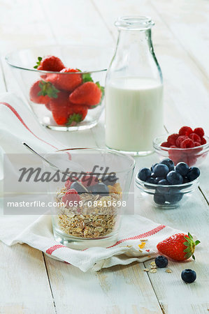 A healthy breakfast: muesli with fresh fruit and milk, strawberries, raspberries, blueberries on a wooden table