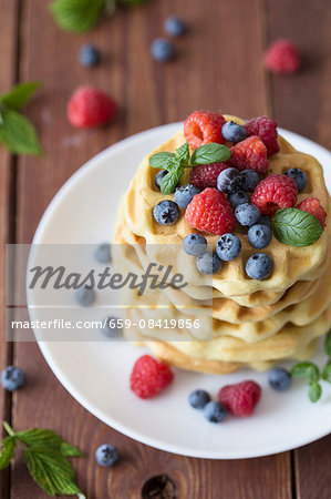 A stack of Belgian waffles with raspberries and blueberries