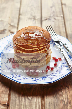 A stack of pancakes with honey and pomegranate seeds