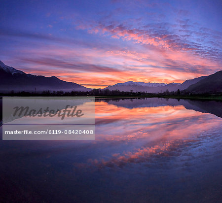 Panoramic view of Pian di Spagna flooded with snowy peaks reflected in the water at sunset, Valtellina, Lombardy, Italy, Europe