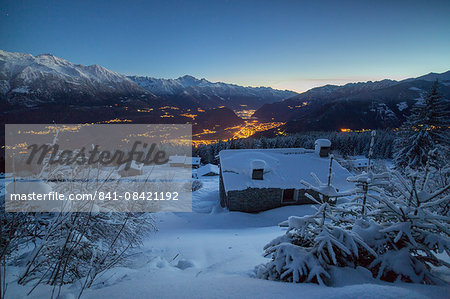 Lights of dusk illuminate the valley and the snow covered huts, Tagliate Di Sopra, Gerola Valley, Valtellina, Lombardy, Italy, Europe