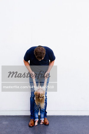 Portrait of mature man with daughter leaning back in front of white wall