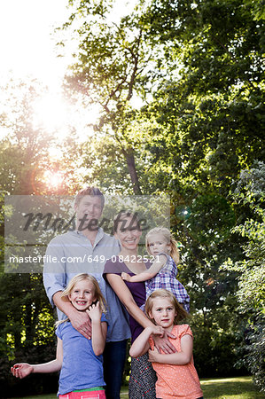 Portrait of parents and three young daughters in sunlit park