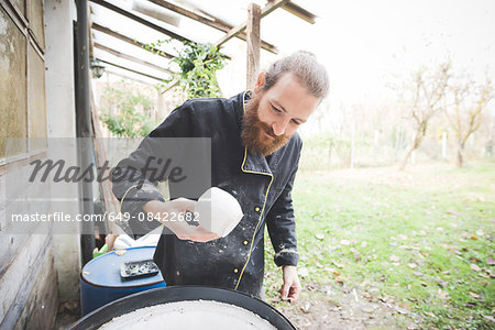 Bearded mid adult man in garden quality checking clay pots