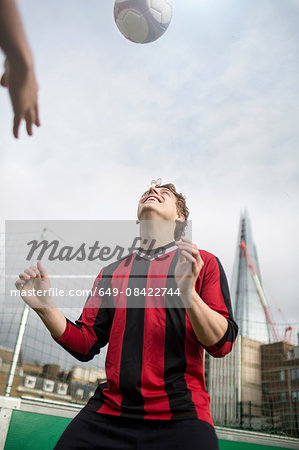 Young man practising football skills on urban football pitch