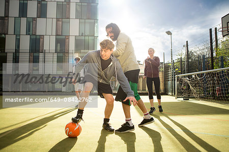 Group of adults playing football on urban football pitch