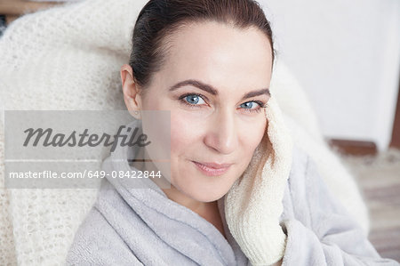 Mature woman touching face with exfoliation glove
